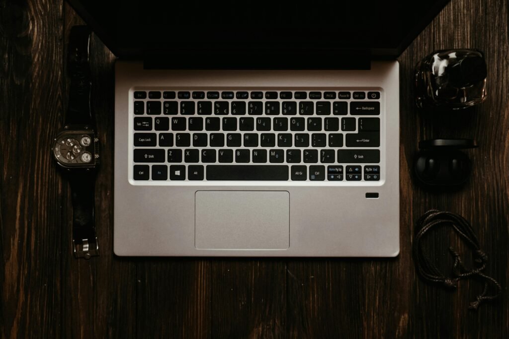 Overhead view of a laptop and tech accessories on a wooden desk. Modern still life.